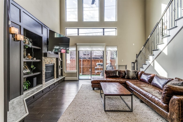 living room with a towering ceiling, a fireplace, and dark hardwood / wood-style floors