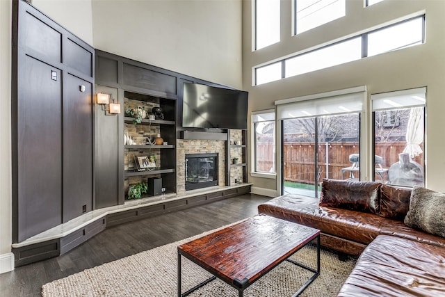 living room with dark hardwood / wood-style floors, a fireplace, built in shelves, and a high ceiling