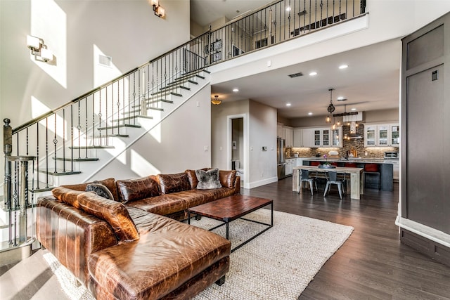 living room with a towering ceiling and dark wood-type flooring