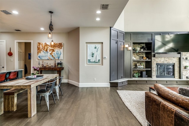 dining room with dark wood-type flooring, a fireplace, and built in shelves