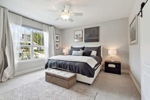 carpeted bedroom featuring a barn door and ceiling fan