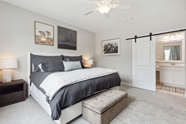 carpeted bedroom featuring ceiling fan, ensuite bathroom, a barn door, and sink