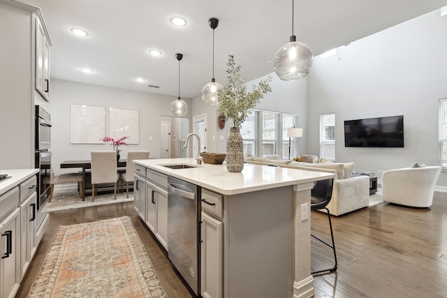 kitchen featuring sink, hanging light fixtures, stainless steel appliances, and an island with sink