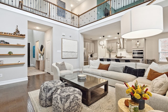 living room with hardwood / wood-style floors, sink, and a high ceiling