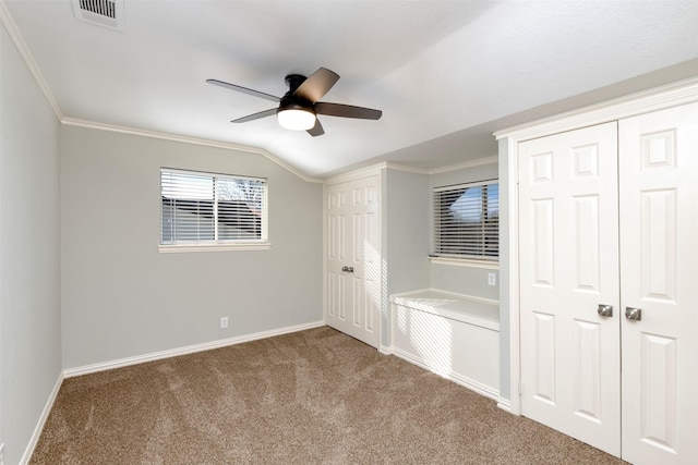 unfurnished bedroom featuring lofted ceiling, ornamental molding, ceiling fan, and carpet