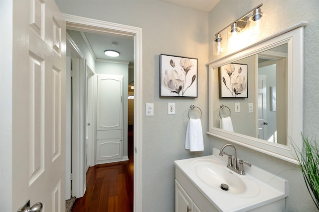 bathroom featuring hardwood / wood-style flooring, ornamental molding, and vanity