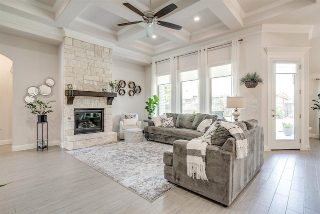 living room featuring coffered ceiling, a fireplace, beamed ceiling, and a healthy amount of sunlight