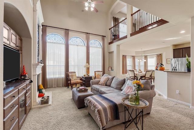 carpeted living room featuring a high ceiling, plenty of natural light, and ceiling fan