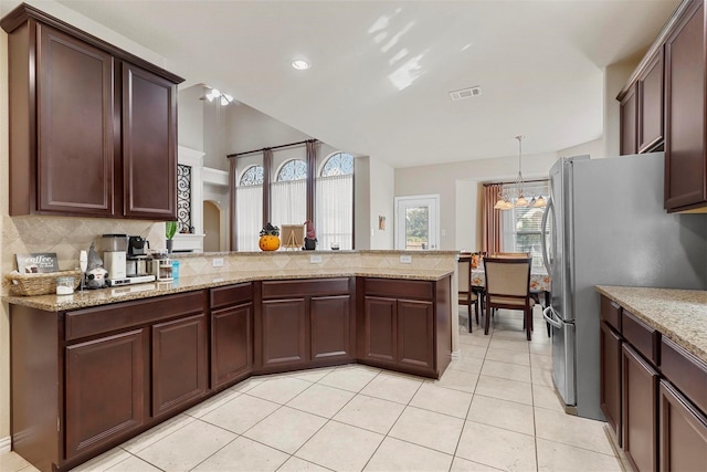 kitchen featuring stainless steel fridge, kitchen peninsula, light stone countertops, and backsplash