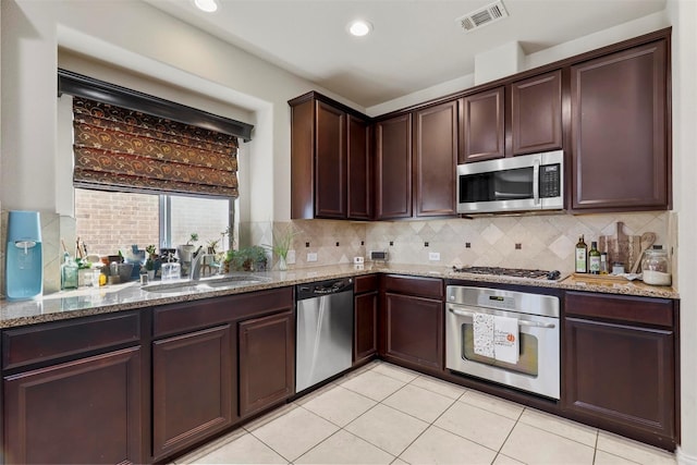 kitchen featuring appliances with stainless steel finishes, sink, light stone counters, and decorative backsplash