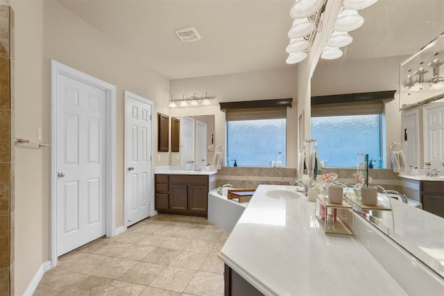 bathroom featuring a notable chandelier, vanity, tile patterned flooring, and a bathtub