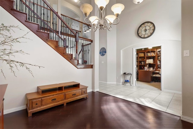 entryway featuring an inviting chandelier, a towering ceiling, and light tile patterned flooring