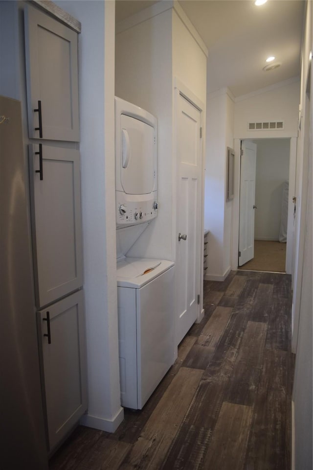 laundry area with dark hardwood / wood-style flooring, crown molding, and stacked washer / dryer