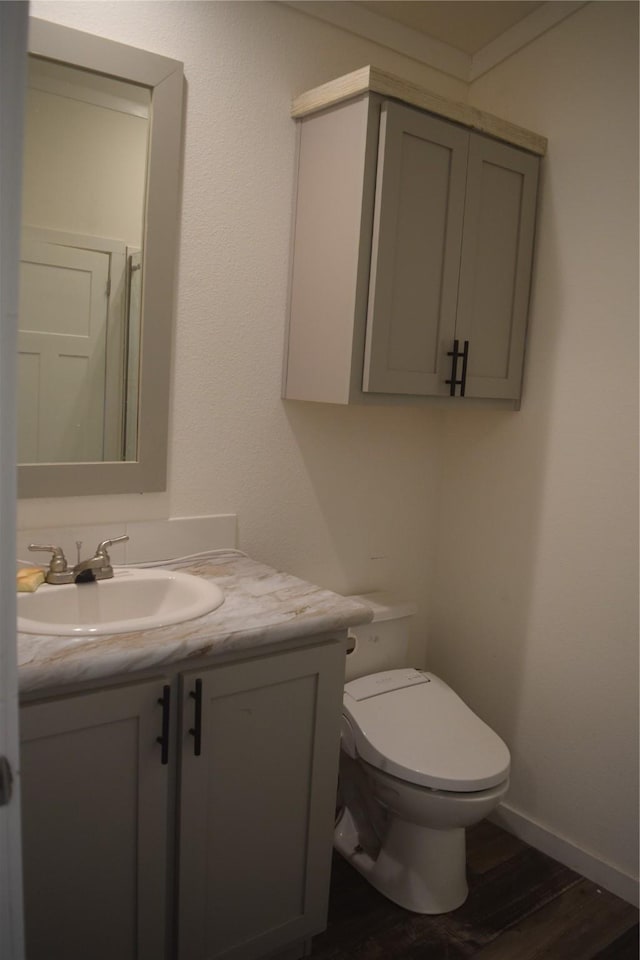 bathroom featuring hardwood / wood-style flooring, vanity, crown molding, and toilet