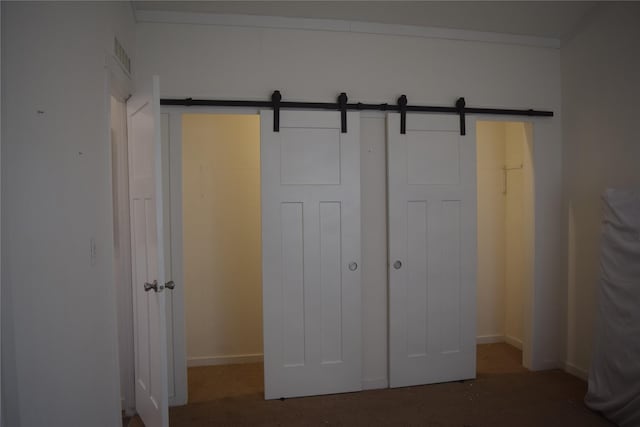 unfurnished bedroom with a barn door and a closet