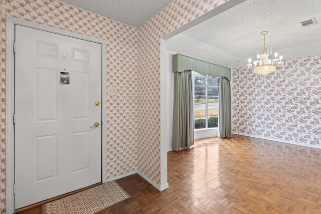 foyer featuring parquet flooring, a notable chandelier, and a textured ceiling