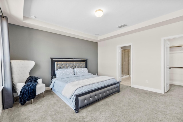 bedroom featuring a walk in closet, a raised ceiling, visible vents, carpet flooring, and baseboards