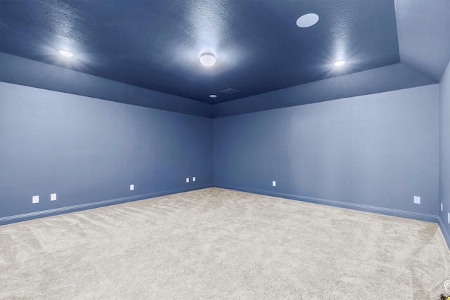 carpeted spare room featuring visible vents, vaulted ceiling, a textured ceiling, and baseboards