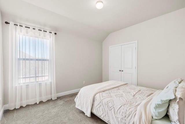 bedroom featuring lofted ceiling, a closet, carpet, and baseboards