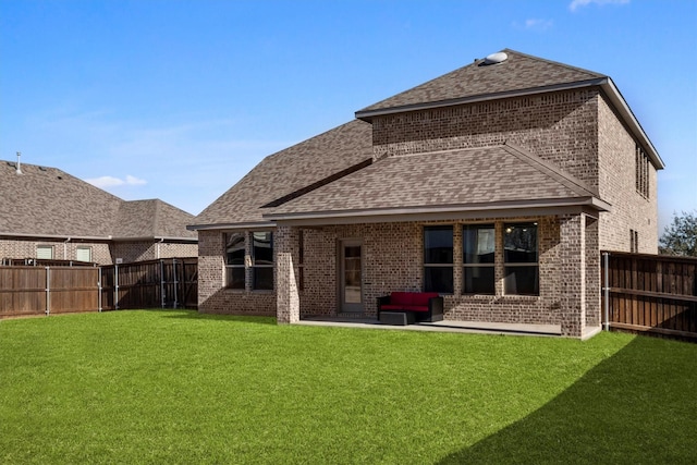 back of house with a yard, a shingled roof, a fenced backyard, and brick siding