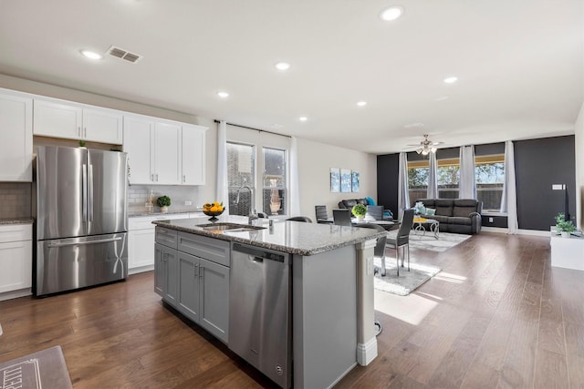 kitchen with tasteful backsplash, visible vents, appliances with stainless steel finishes, light stone countertops, and a sink