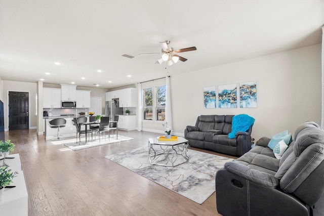 living room with light wood finished floors, visible vents, baseboards, ceiling fan, and recessed lighting