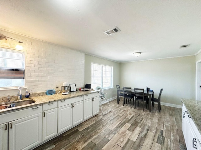 kitchen with sink, ornamental molding, light stone countertops, hardwood / wood-style floors, and white cabinets