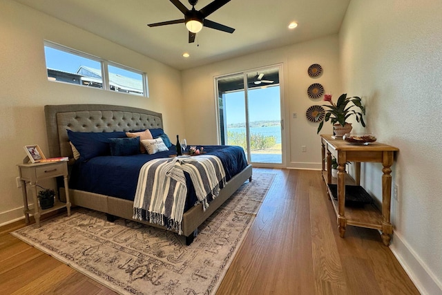 bedroom with access to exterior, multiple windows, baseboards, and wood finished floors