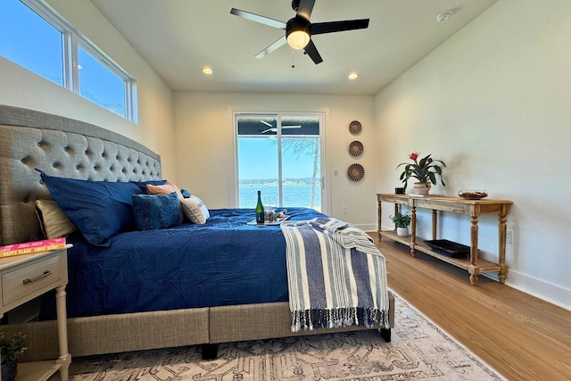 bedroom with access to outside, multiple windows, baseboards, and wood finished floors