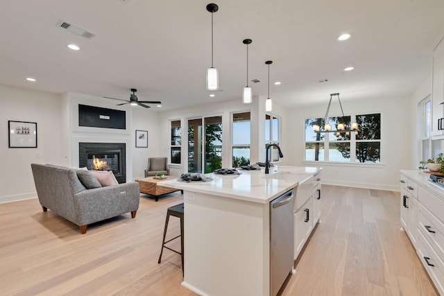 13590 Park Harbor Dr, Eustace, TX 75124 - kitchen featuring light wood-style floors, stainless steel dishwasher, a glass covered fireplace, a sink, and white cabinetry