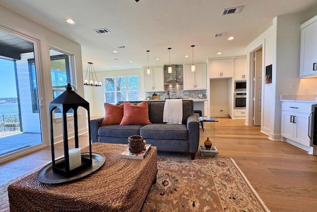 living area with light wood-style flooring and visible vents