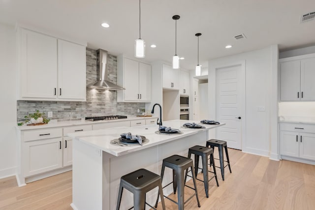 13590 Park Harbor Dr, Eustace, TX 75124 - kitchen with wall chimney exhaust hood, light wood-style flooring, gas cooktop, decorative backsplash, and a kitchen bar
