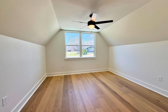 additional living space with a ceiling fan, lofted ceiling, baseboards, and wood finished floors