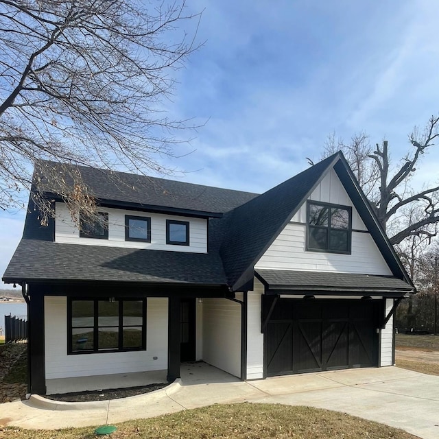 modern farmhouse with covered porch, driveway, roof with shingles, and a garage