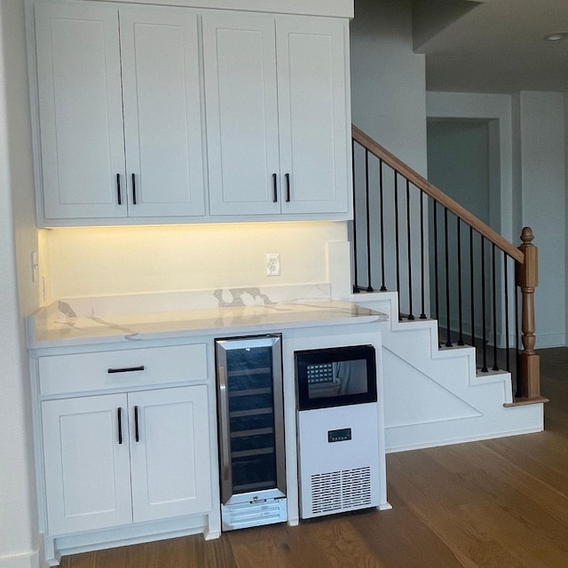 bar featuring wine cooler, dark hardwood / wood-style floors, light stone countertops, and white cabinets