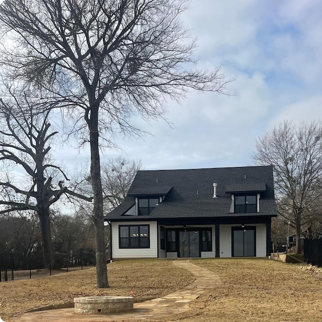 rear view of house featuring roof with shingles and fence