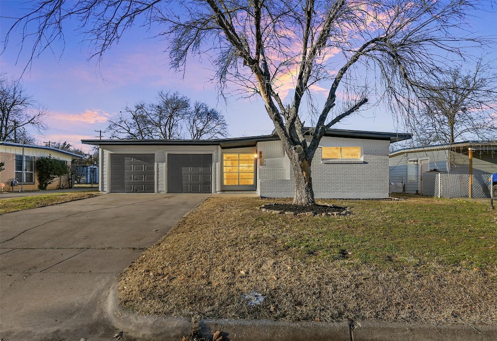 ranch-style house featuring a garage and a lawn