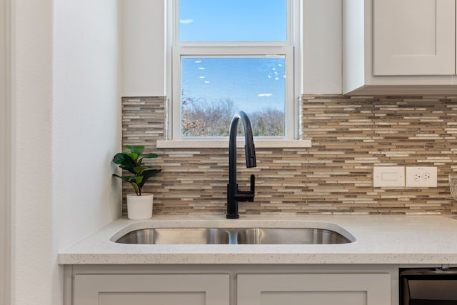 kitchen featuring white cabinets, light stone countertops, sink, and backsplash