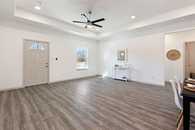 interior space with ceiling fan, dark hardwood / wood-style floors, and a raised ceiling