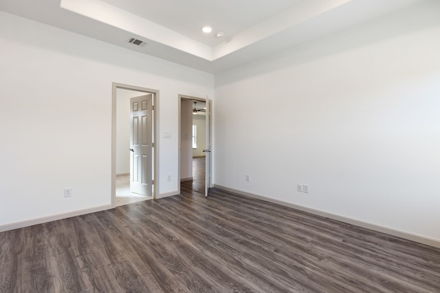 unfurnished bedroom featuring a raised ceiling and dark hardwood / wood-style floors