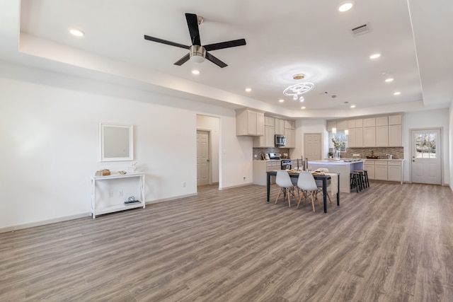 dining room featuring a tray ceiling, light hardwood / wood-style floors, and ceiling fan