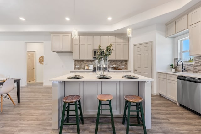 kitchen with sink, a center island, light hardwood / wood-style flooring, dishwasher, and pendant lighting