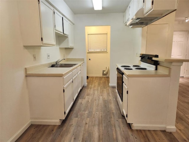 kitchen with electric stove, sink, and white cabinetry