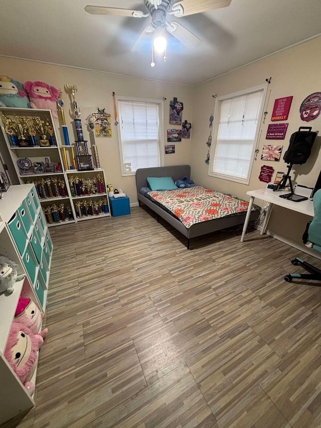 bedroom featuring multiple windows, hardwood / wood-style flooring, and ceiling fan