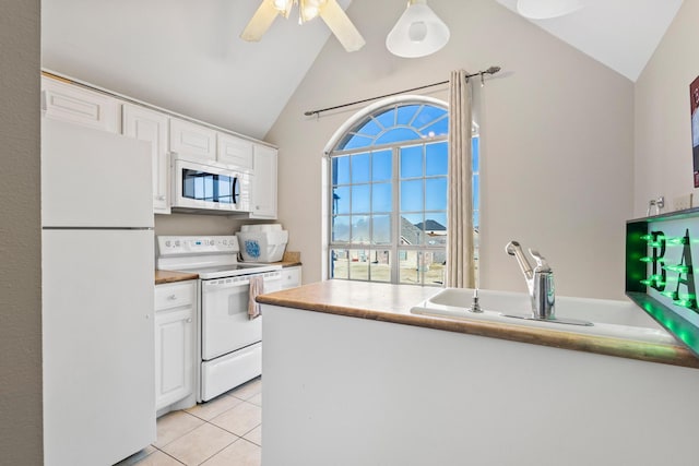 kitchen with lofted ceiling, light tile patterned floors, white appliances, sink, and white cabinetry