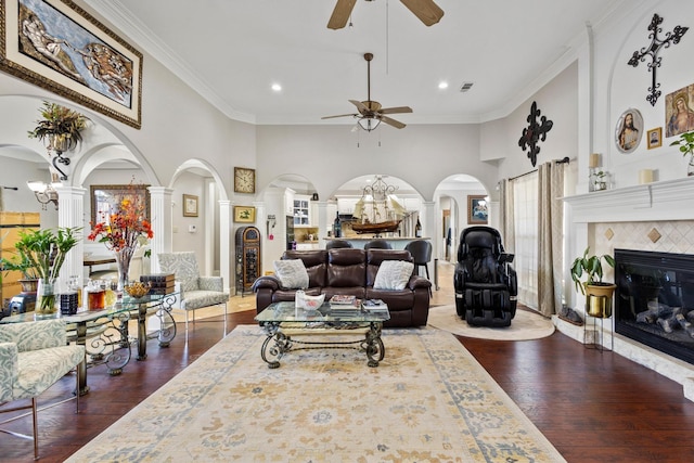 living room with dark hardwood / wood-style floors, a towering ceiling, ornamental molding, and a fireplace