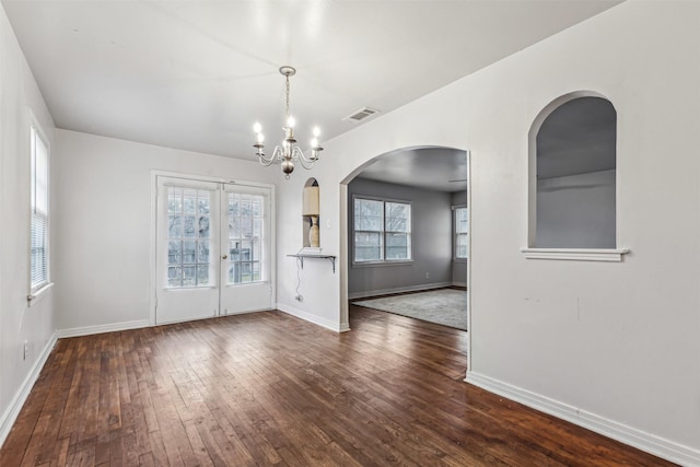 unfurnished dining area with dark hardwood / wood-style flooring and a notable chandelier