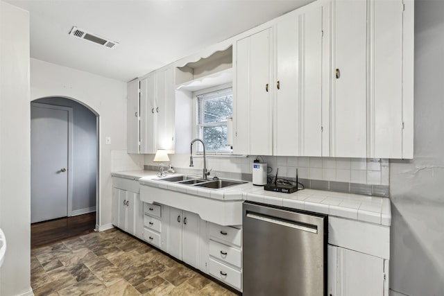 kitchen with sink, tile countertops, dishwasher, white cabinets, and backsplash