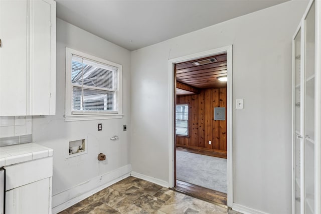 washroom with electric dryer hookup, hookup for a washing machine, wooden walls, cabinets, and hookup for a gas dryer