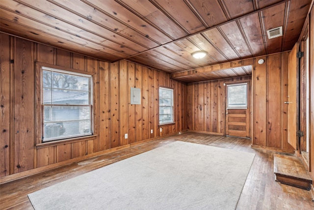 spare room featuring wood ceiling, wood-type flooring, wooden walls, and electric panel